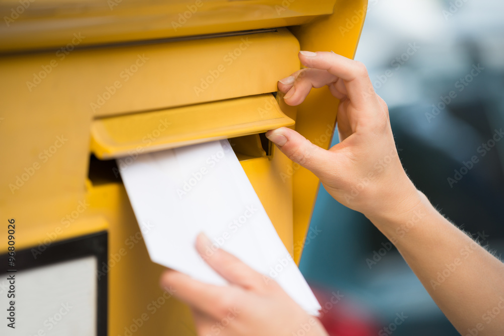 Woman's Hands Inserting Letter In Mailbox