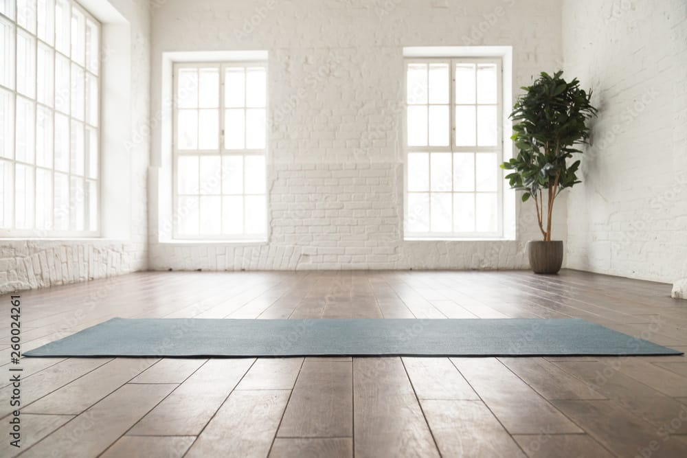 Unrolled yoga mat on wooden floor in yoga studio and yoga studio marketing